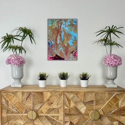Decorative setup with a wooden cabinet, potted plants, and a colorful abstract painting on a white wall.
